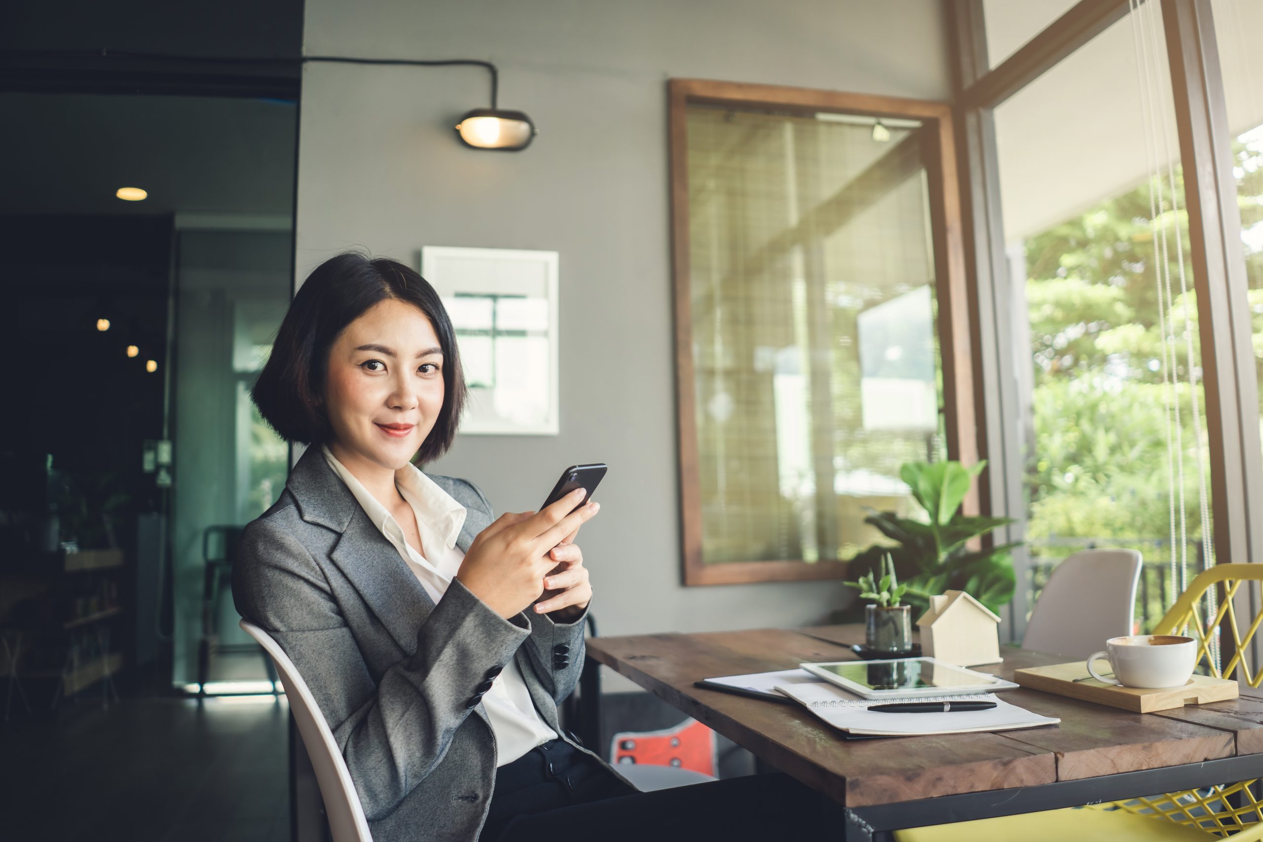 Asian,Businesswoman,Working,And,Holding,Smartphone,Sitting,In,Coffee,Shop